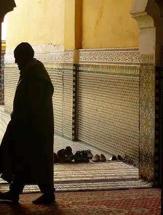 architecture-marocaine-zellige-silhouette Silhouette d'un homme marchant sous une arche mauresque avec des mosaïques en zellige au Maroc.