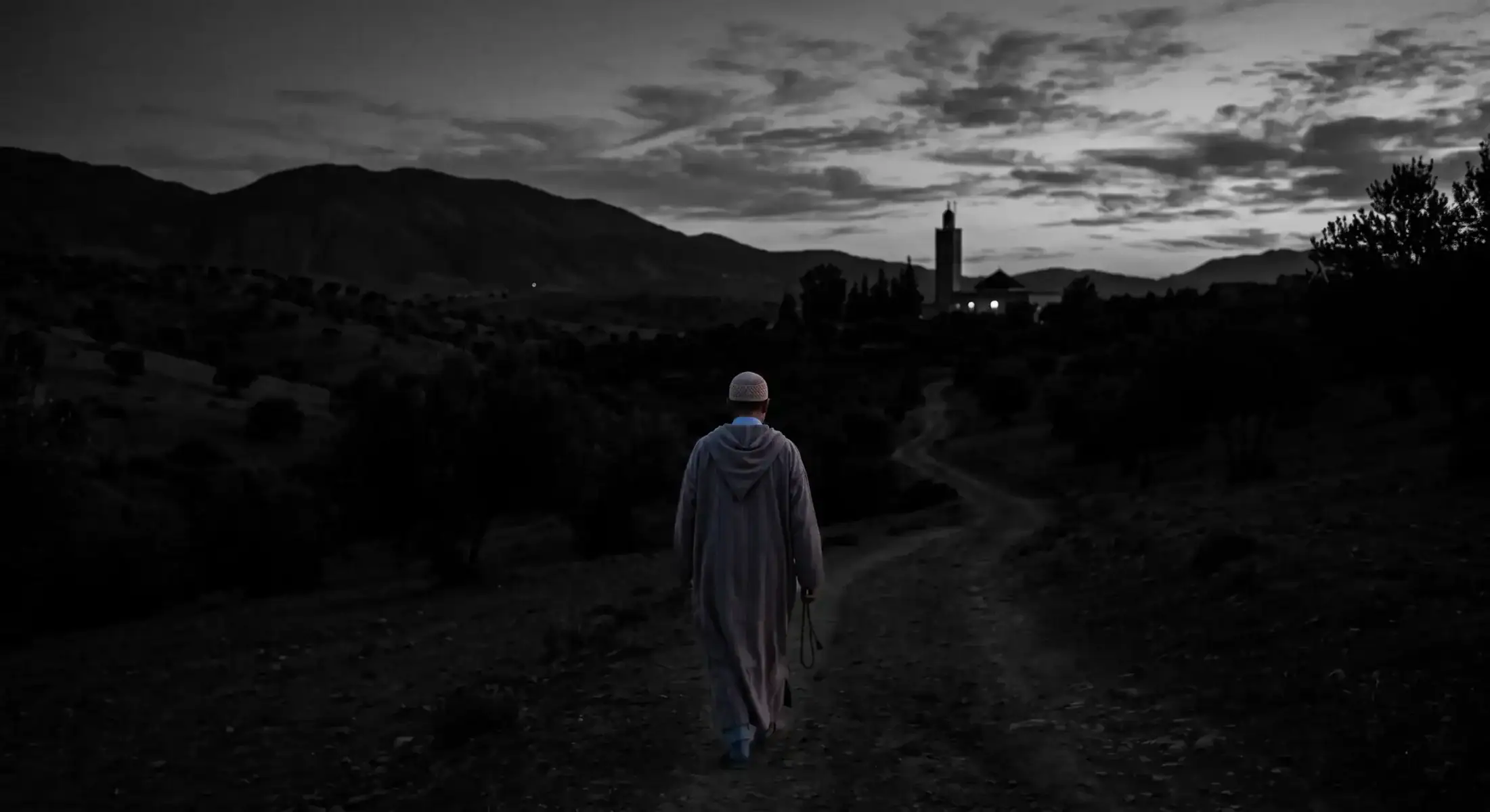 priere-fajr-aube-spiritualite-musulmane Silhouette d'un homme marchant vers une mosquée à l'aube pour la prière du Fajr, sous un ciel aux teintes orangées et violettes.