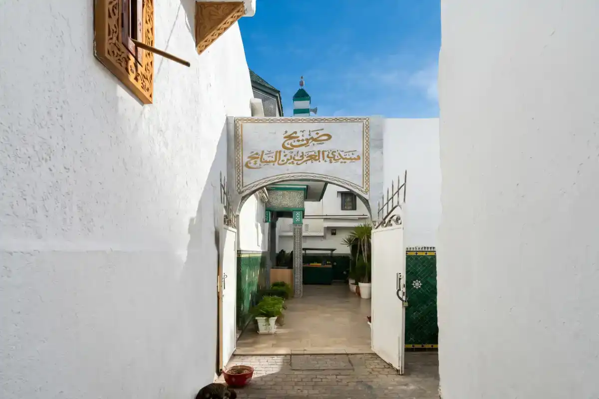 Entrée du mausolée de Sidi Larbi Ben Sayeh à Rabat, avec sa porte traditionnelle en bois sculpté et ses murs ornés de zelliges et de plâtre ciselé.