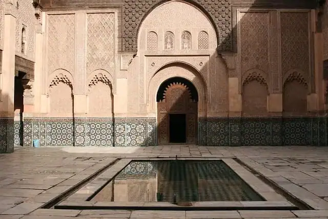 medersa-ben-youssef-marrakech-architecture Soufisme Sunnite au Maroc : vue intérieure de la Médersa Ben Youssef à Marrakech, montrant le bassin central, la cour de marbre et les façades ornées de zelliges et de cèdre sculpté.