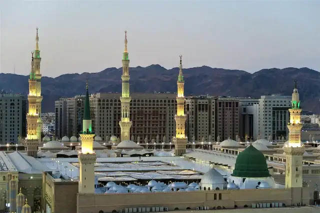 mosquee-du-prophete-al-masjid-an-nabawi-medine Vue extérieure de la Mosquée du Prophète (Al-Masjid an-Nabawi) à Médine, mettant en évidence les minarets blancs et l'architecture sacrée sous un ciel clair.