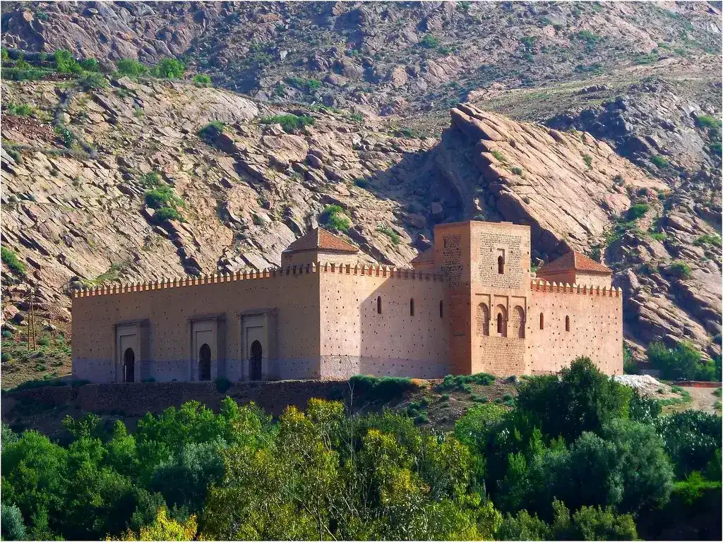 Ruines de la mosquée historique de Tinmel dans le Haut Atlas marocain, montrant les arches en briques rouges et les structures en pisé contre les montagnes