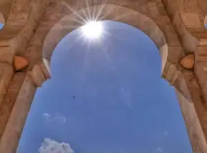 Vue à travers l'arche en pierre de la Grande Mosquée de Taza au Maroc avec le soleil brillant dans le ciel bleu.