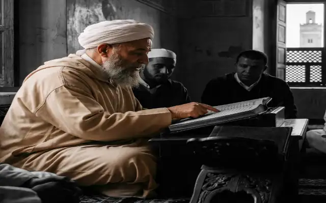 savant-souss-transmission-sciences-islamiques-maroc savant de la région du Souss en djellaba et turban, enseignant les sciences islamiques à des étudiants attentifs dans une école traditionnelle (madrassa) au Maroc.