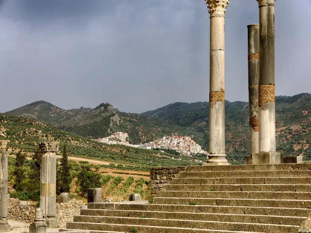Vue des colonnes romaines de Volubilis avec, en arrière-plan, les collines verdoyantes du massif de Zerhoun au Maroc.