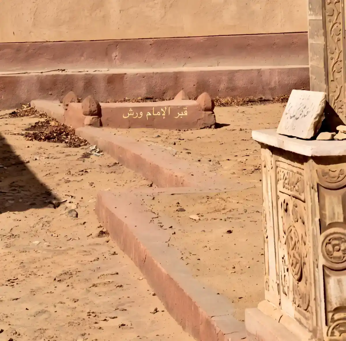 Tombe de l’Imam Warch, célèbre récitateur du Coran Vue de la tombe de l'Imam Warch. L'inscription en arabe lisible sur la structure indique « Tombe de l'Imam Warch » (قبر الإمام ورش).